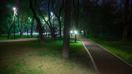 Running track in the city park at night illuminated by lanterns. Running and walking in the fresh air