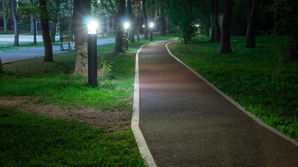 Running track in the city park at night illuminated by lanterns. Running and walking in the fresh air
