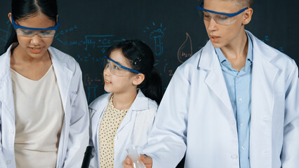 Smart girl pour colored solution in to beaker while diverse student excited about doing experiment....