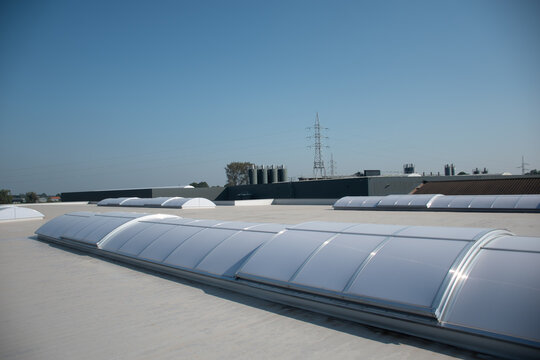 Kunststof koepel op plat dak van groot gebouw, plat dak met veel grote dakramen en modern industrieel gebouw
