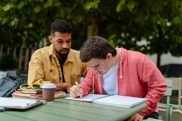 Young man with Down syndrome studyng with special educator teacher.