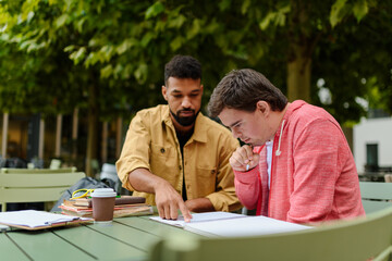 Young man with Down syndrome studyng with special educator teacher.