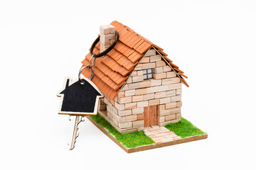 Casa en miniatura con una llave enganchada en la chimenea, aislado en blanco