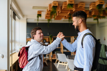 Young man with Down syndrome greeting his teacher in school.