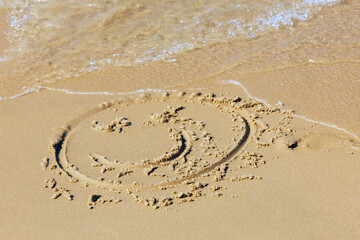 A painted smiley face on the beach sand
