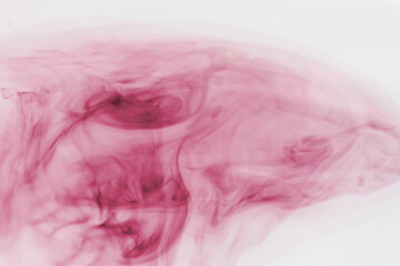 color cloud of red ink in water forming tatters and strips of color