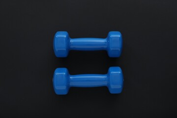 Dumbbells on black background, top view. Sports equipment