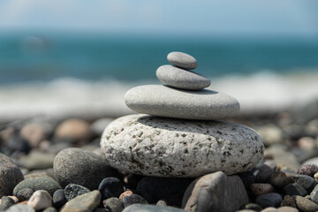 A pyramid of sea pebbles on a sunny pebble beach. The concept of life balance and harmony