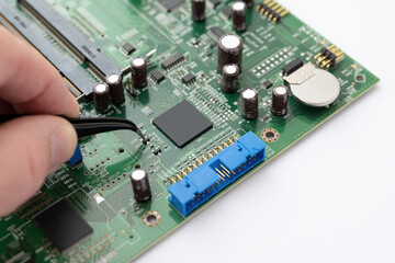 Technician repairing electronic circuit board with tweezers

