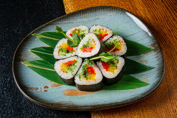Colorful Sushi Rolls Beautifully Arranged on a Stylish Plate With Fresh Greens on Display in an Elegant Dining Setting for a Culinary Delight.