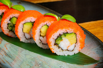 Colorful Sushi Rolls Topped With Vibrant Orange Roe, Showcasing Fresh Ingredients on an Elegant Plate in a Cozy Dining Setting.