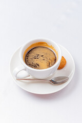 Rich Dark Coffee Served in a White Cup With a Delicate Spoon and Buttery Biscuit on a Simple Plate, Perfect for a Cozy Afternoon Break.