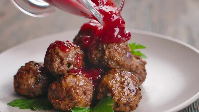 Prepared cranberry sauce is poured over Swedish meatballs. Close-up. High quality 4k footage