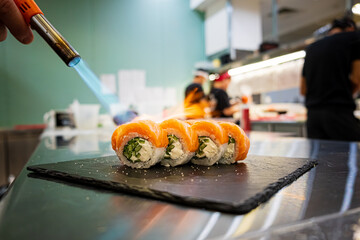 Delicate Sushi Preparation Unfolding in a Vibrant Kitchen as a Chef Uses a Torch to Enhance Flavors...