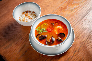 Delicious Seafood Soup Served Alongside a Fragrant Bowl of Rice on a Rustic Wooden Table.