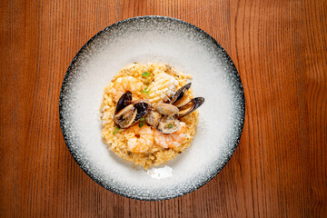 Seafood Risotto Garnished With Fresh Shellfish Served on an Elegant Dish in a Cozy Dining Setting.