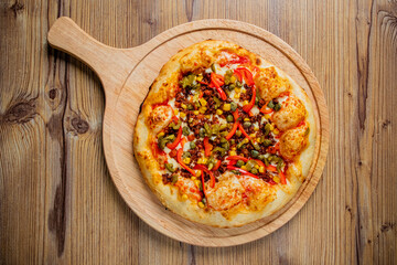 Savoring a Delicious Homemade Pizza Topped With Vibrant Vegetables and Savory Meat on a Rustic Wooden Table.