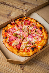 Savoring Deliciously Crafted Pizza Topped With Ham, Mushrooms, Onions, and Pickles, Presented in a Rustic Takeout Box on a Wooden Table.