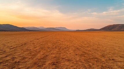 A vast, arid landscape with golden earth and distant mountains under a colorful sunset sky.