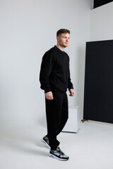 A Stylish Man Dressed in Black Athleisure Attire is Confidently Walking Along the Street