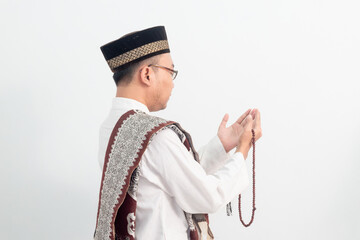 Asian Muslim man wearing white clothes doing praying hand pose during Ramadan Eid Al Fitr and eid...