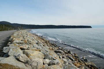 Rocky shoreline with winding road under cloudy sky