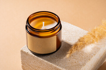 Mock-up of aroma soy candle in amber glass jar on natural stone pedestal. Scented cozy atmosphere...