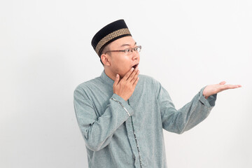 Asian Muslim man smiling showing product gesture in Ramadan Eid Al Fitr and eid adha days celebration isolated white background. Islamic celebration concept..
