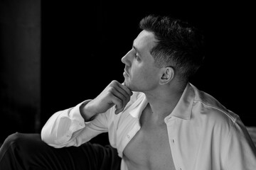 Young sexy handsome fit stylish man in a white shirt with naked torso looking at the camera in the studio. Close up portrait, casual clothes, modern style