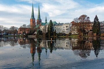 Obraz premium Der Lübecker Dom spiegelt sich im Winter im vereisten Mühlenteich, Deutschland