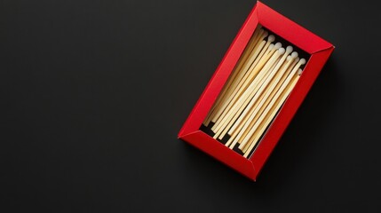 Red matchbox filled with wooden matches on black background