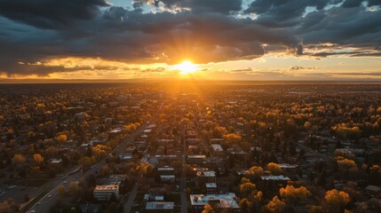 Aerial view of a city at sunset with golden hour light and dramatic clouds.