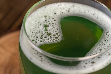 a green carbonated drink made with herbs with white foam