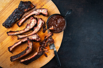 Barbecue spareribs St Louis cut with hot rub and BBQ sauce served as top view on a wooden design board with copy space right