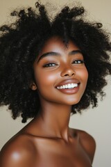 Smiling young woman with curly hair posing for a portrait against a neutral background