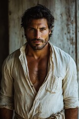 Handsome man in casual linen shirt poses confidently against rustic wooden background