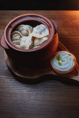 Hot, juicy dumplings snuggled in a pot. Next to it is a spoonful of sour cream to make this dish even tastier.
