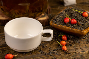 red rosehip fruits and hot green tea in a transparent teapot