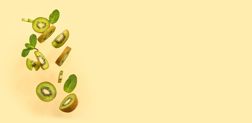 Flying cut kiwi and mint leaves against color background
