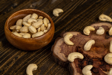 large cashew nuts are scattered on a larch board