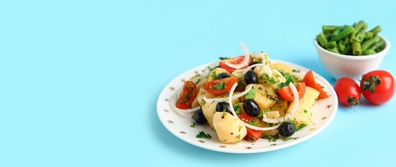 Plate of tasty potato salad on light blue background with space for text