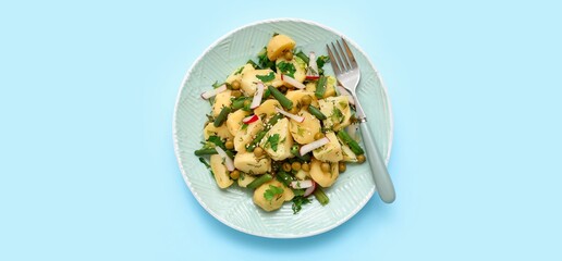 Plate of tasty potato salad on light blue background, top view