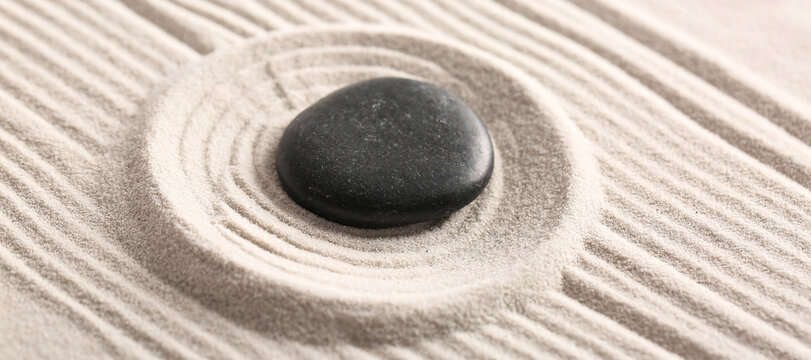 Black stone on light sand with pattern. Zen concept