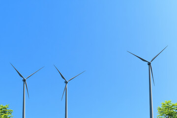 Fototapeta premium Three wind turbines are standing tall in the sky