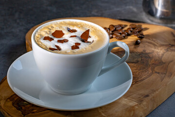 Cappuccino with coffee beans in a white cup on a dark background