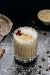 Creamy latte with coconut flakes and dried rose garnish, served in a glass with a velvety frothy top