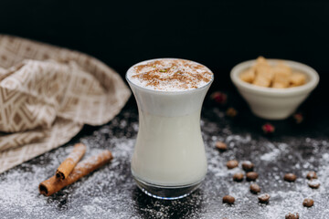 Creamy spiced milk drink in a stylish glass, topped with cinnamon and coconut flakes
