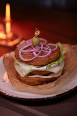 Juicy burger made from draniki and meat patties, lettuce, onion on top and olive. A delicious photo for a menu, culinary website, or an advertisement for catering establishments