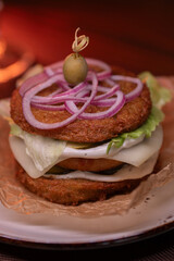 Juicy burger made from draniki and meat patties, lettuce, onion on top and olive. A delicious photo for a menu, culinary website, or an advertisement for catering establishments