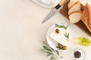 Plate with tasty feta cheese, olives, rosemary and bread on white background